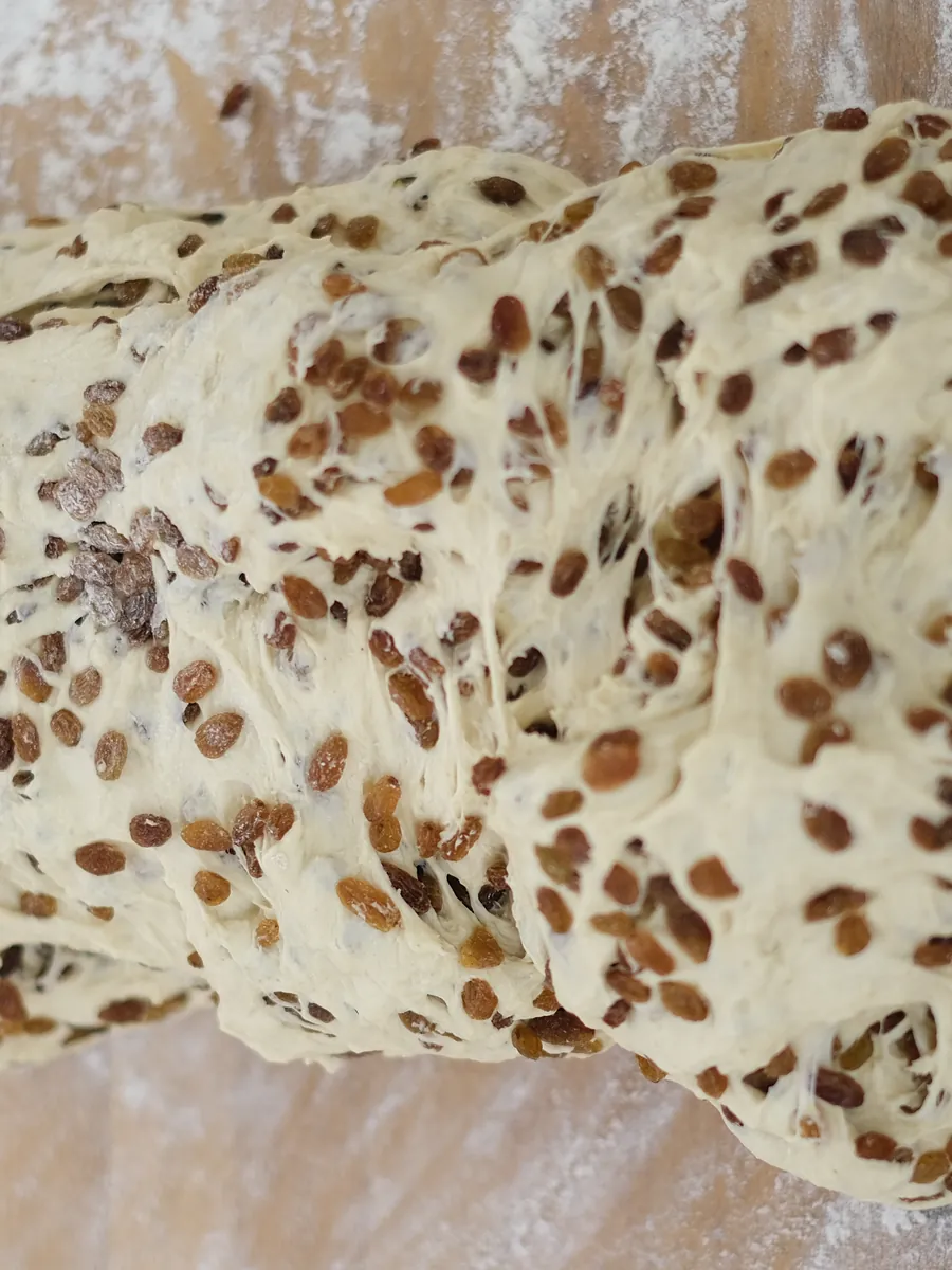 Teig mit eingearbeiteten Früchten auf einem bemehlten Holzbrett