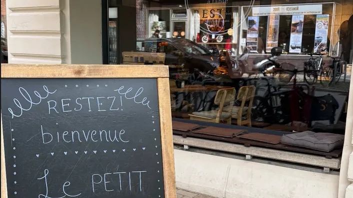 Kreidetafel „Restez! bienvenue“ vor dem Schaufenster in der Legienstraße
