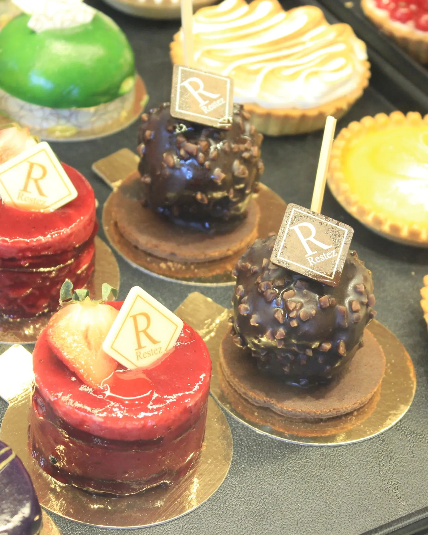 Vitrine mit Törtchen, Tartes und Entremets mit Restez!-Plakette